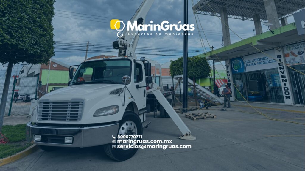 Grúa Titán estabilizada durante el montaje de un poste metálico en una zona comercial.