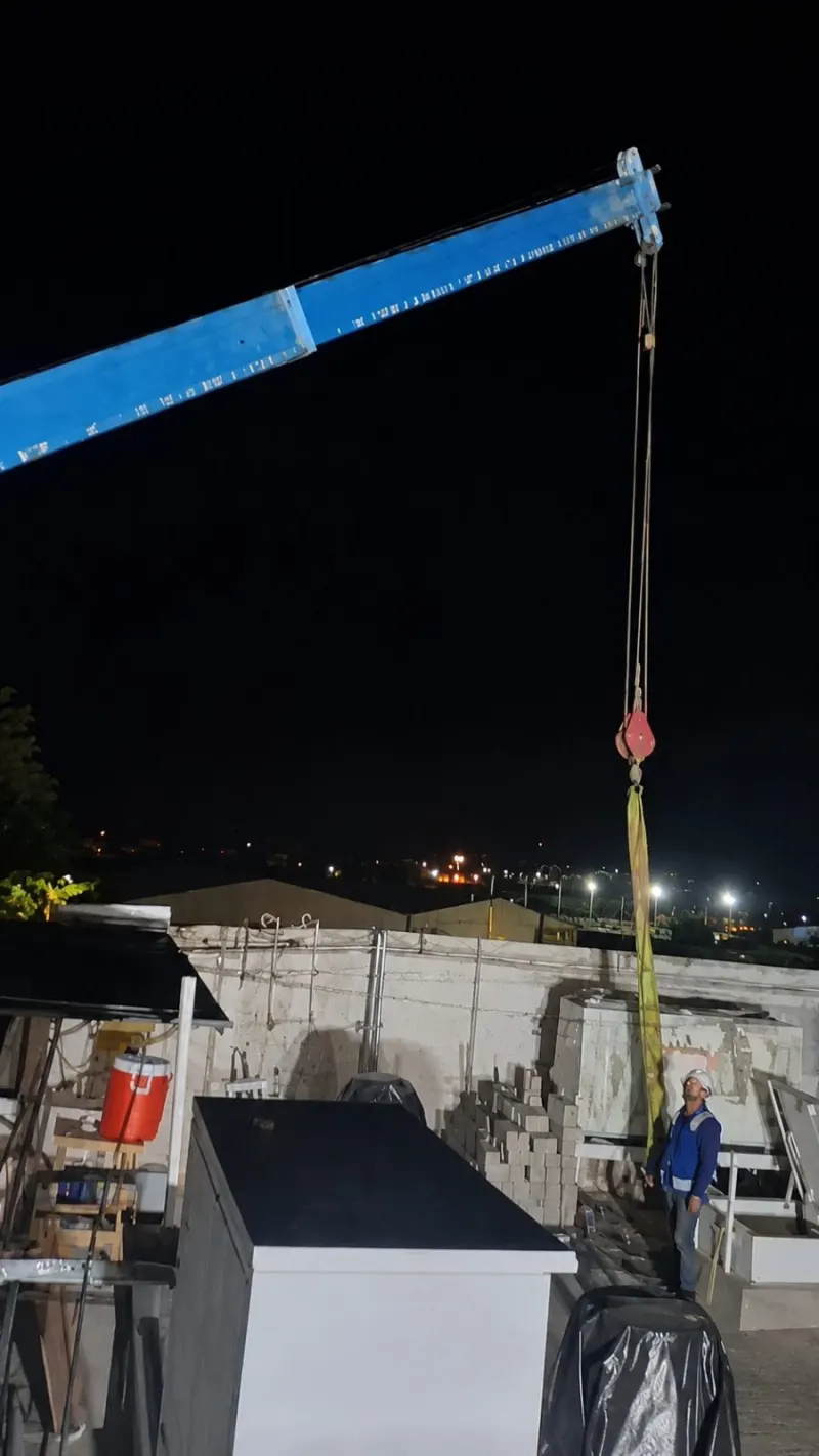 Vista frontal de la grúa Titán con estabilizadores desplegados y la pluma extendida frente al inmueble.