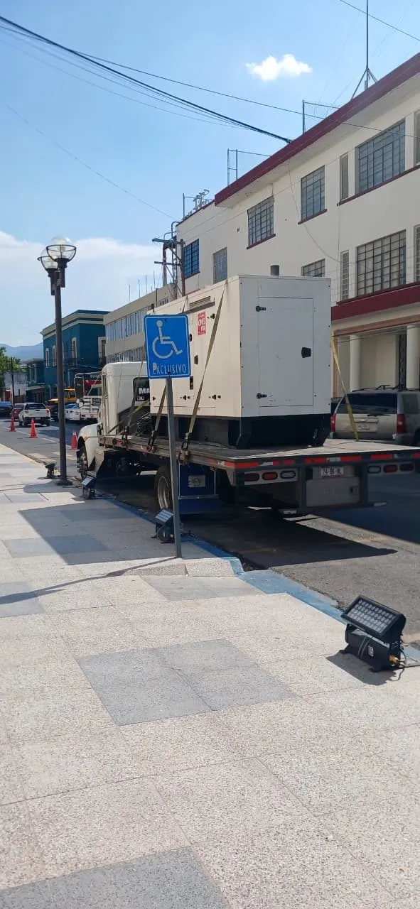 Planta de luz sobre el pavimento, junto a la parte trasera del camión y una barrera metálica.