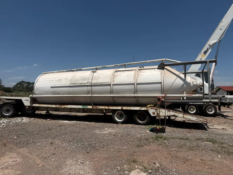 Silo metálico colocado horizontalmente sobre una cama baja y asegurado con cadenas.