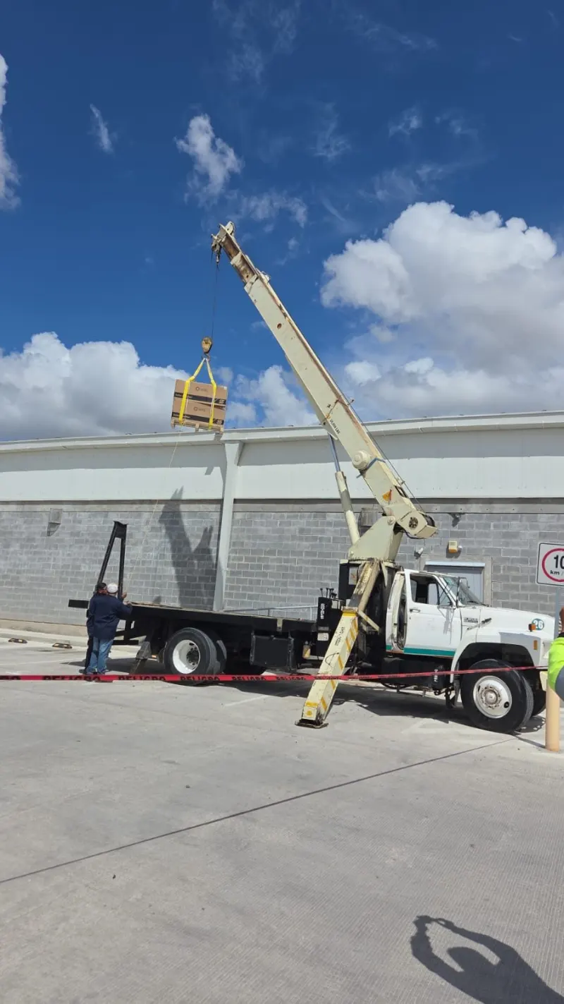 Montacargas amarillo retira una tarima envuelta del interior de un camión de caja abierta.