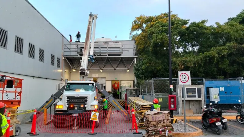 Grúa Titán ingresando a una planta industrial entre tarimas, equipos y personal de apoyo.