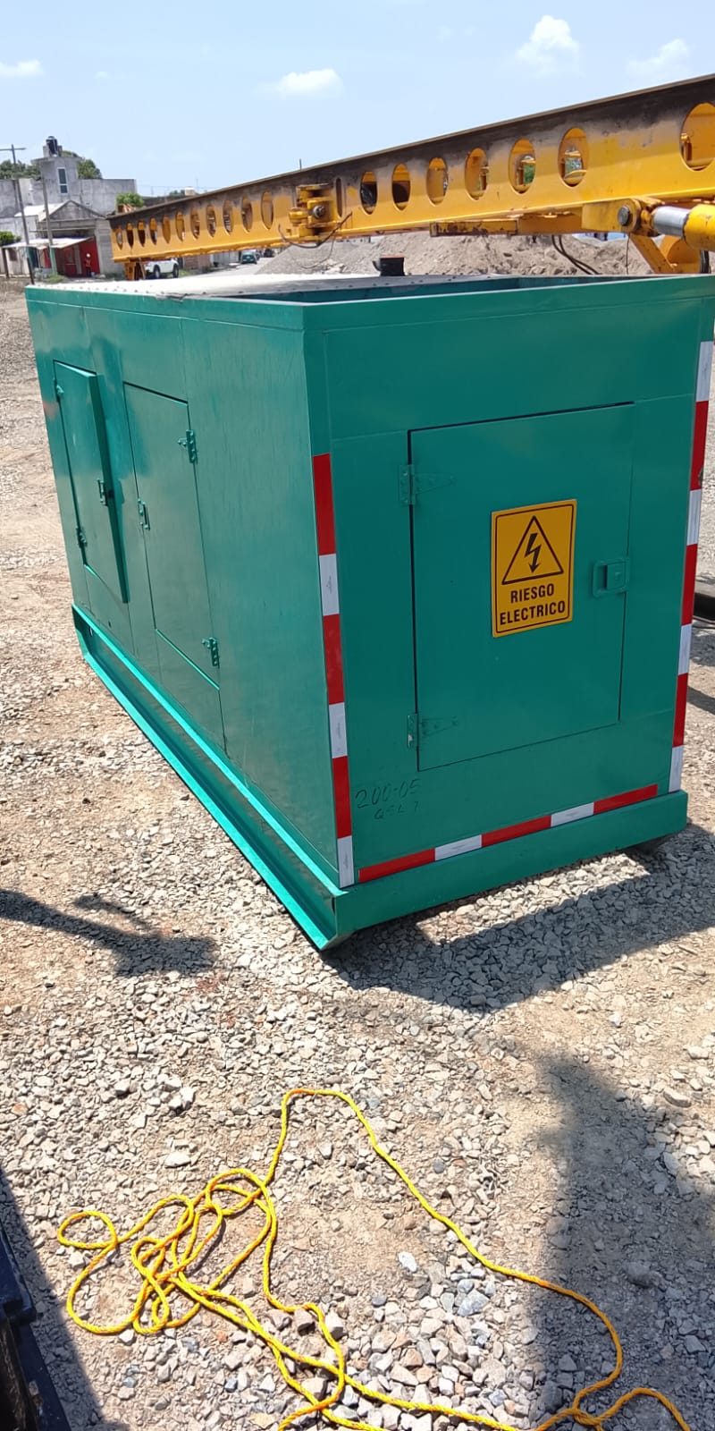 Planta eléctrica encapsulada de color verde colocada sobre una superficie de grava.