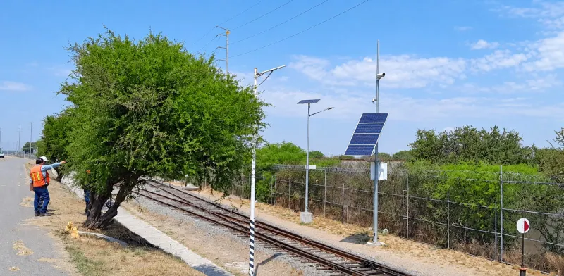Canastilla con personal junto a un panel solar; otro trabajador está en una escalera al pie del poste.