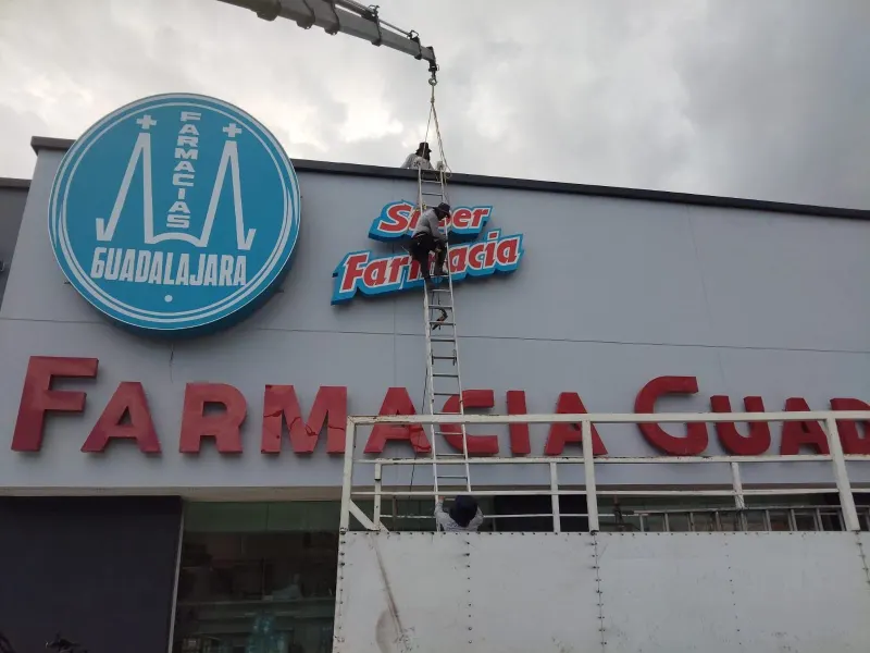 Camión con grúa HIAB junto a una fachada comercial, con la pluma extendida sobre el letrero.