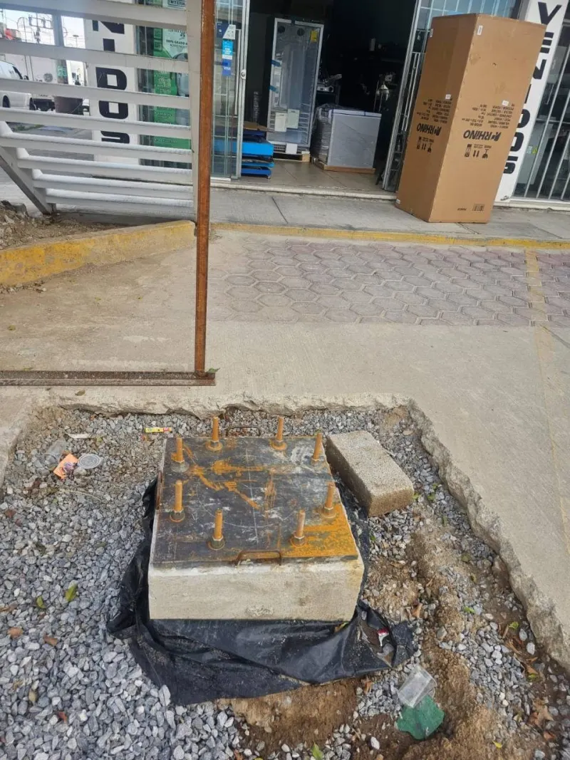 Base de concreto con placa metálica y pernos de anclaje preparados para recibir el poste.
